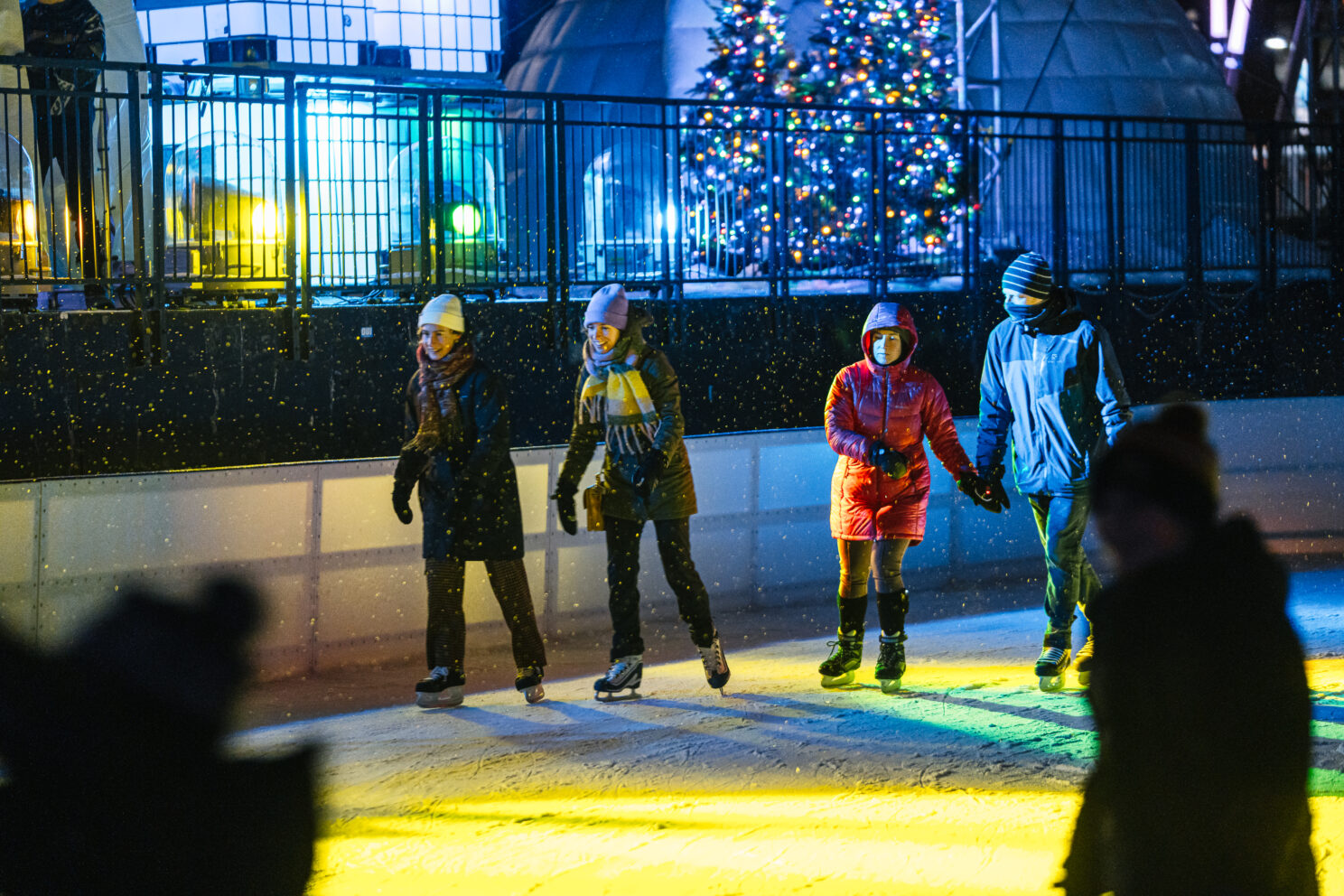 quelques personnes qui patinent devant les lumières de la scène