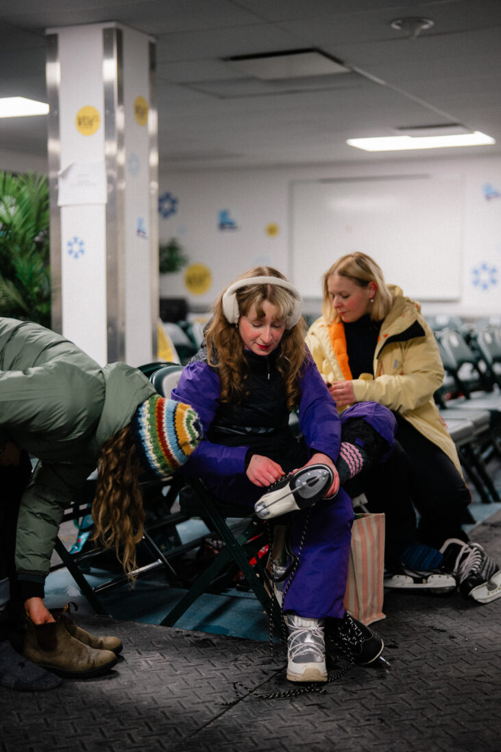 three girls putting their skates on before going ice skating